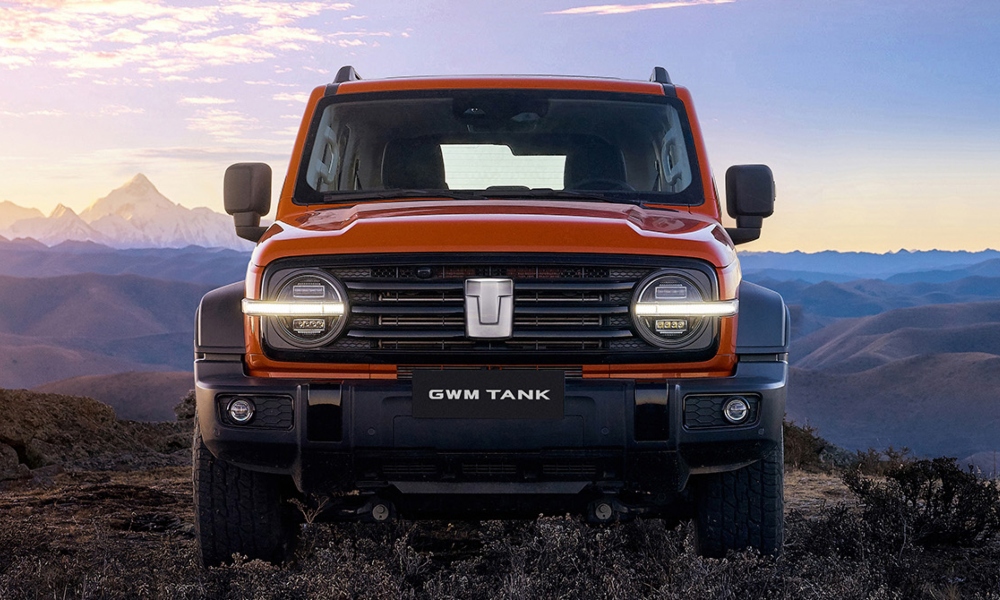 SUV todoterreno de lujo color naranja con luces led futuristas y fondo de montañas.